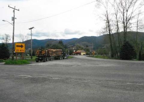 Railroad crossing of the historic SR 9 segment at curves in Van Zandt, MP 77.38, with logging truck on roadside.