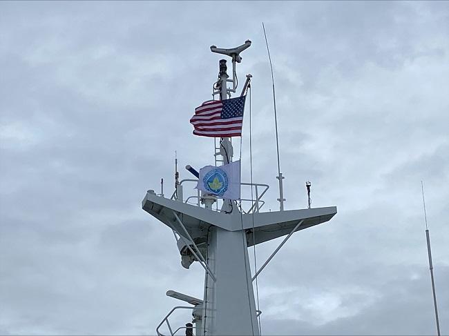 American and Green Marine flags flying atop a ferry