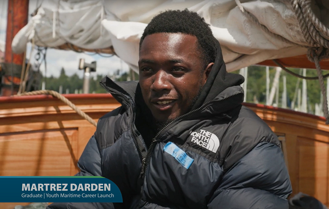 Screenshot from a video of a person on a boat with text on screen reading "Martrez Darden, Graduate, Youth Maritime Career Launch