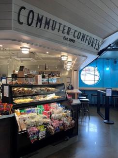 Commuter Comforts inside Bainbridge terminal with an assortment or drinks, food and snacks on display on left and a seating area on right
